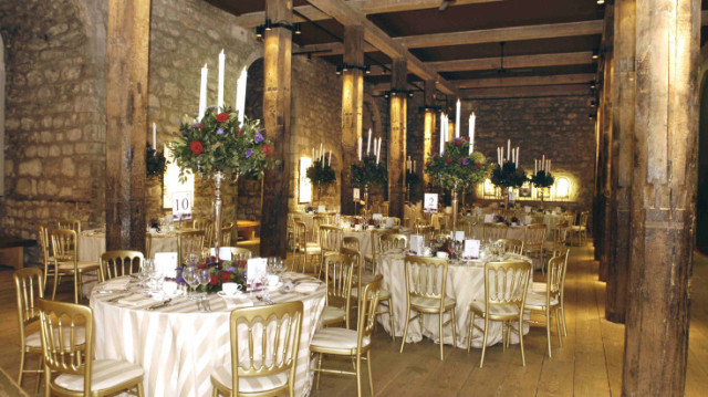 White Tower Suite set for a dinner party with grand windows and exposed brick work with round tables dressed in white linen tall tall floral centre pieces Tower of London Christmas Party EC3