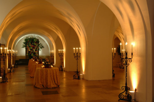 Undercroft with arched ceilings up light in gold room for a standing reception space with poser tables and candelabras Banqueting House Venue Hire SW1