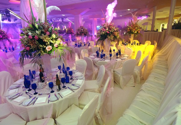 Round tables and benches dressed in white linen with bright floral displays in the Sheridan Suite Venue Hire M40