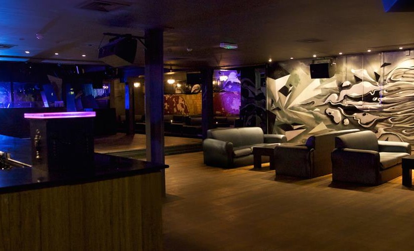 Qube Project Venue Hire SW1, large open space dancing area, lighted bar, sofa seating area with black and white backdrop