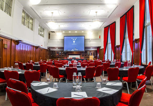 Council Chamber set in cabaret style with half moon tables and presentation screen at the front of the room with large open windows and lots of natural daylight Hallam Conference Venue Hire W1