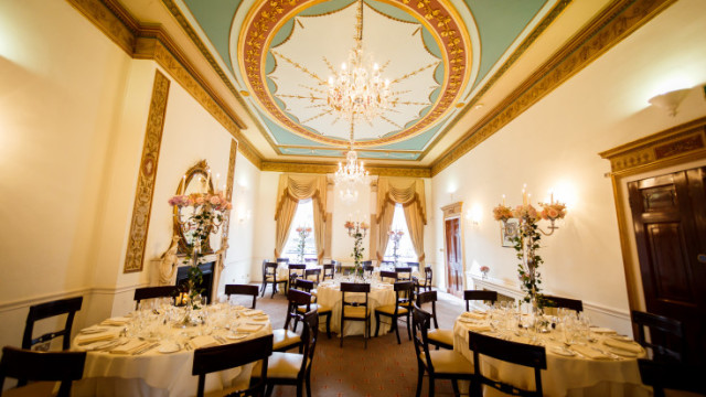 Heggie Room set for dinner with round tables dressed in white linen and a chandelier in the centre of the room 28 Portland Place Venue Hire W1