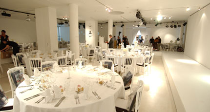 Henry Moore Gallery set for a christmas party with large round tables in between the room's pillars all dressed in white linen to match the blank canvas space Royal College of Art Venue Hire SW7