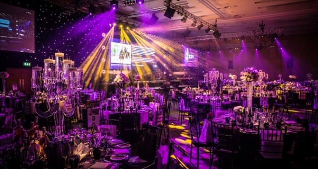 Deansgate Suite set for a large christmas party with high ceilings projecting light patterns, large screens on the walls and round tables set for dinner Hilton Manchester Deansgate Christmas Party M3